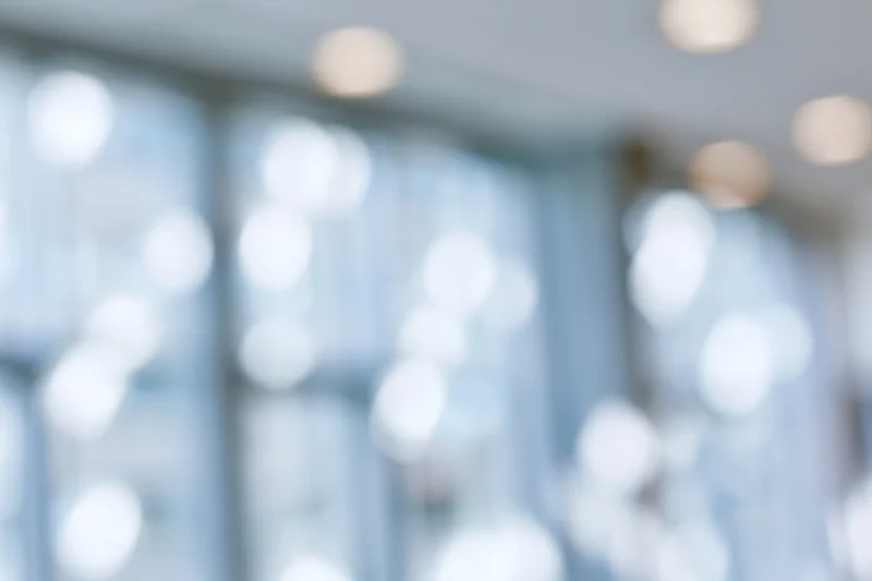 Blurred interior space with soft bokeh lights from ceiling fixtures and windows