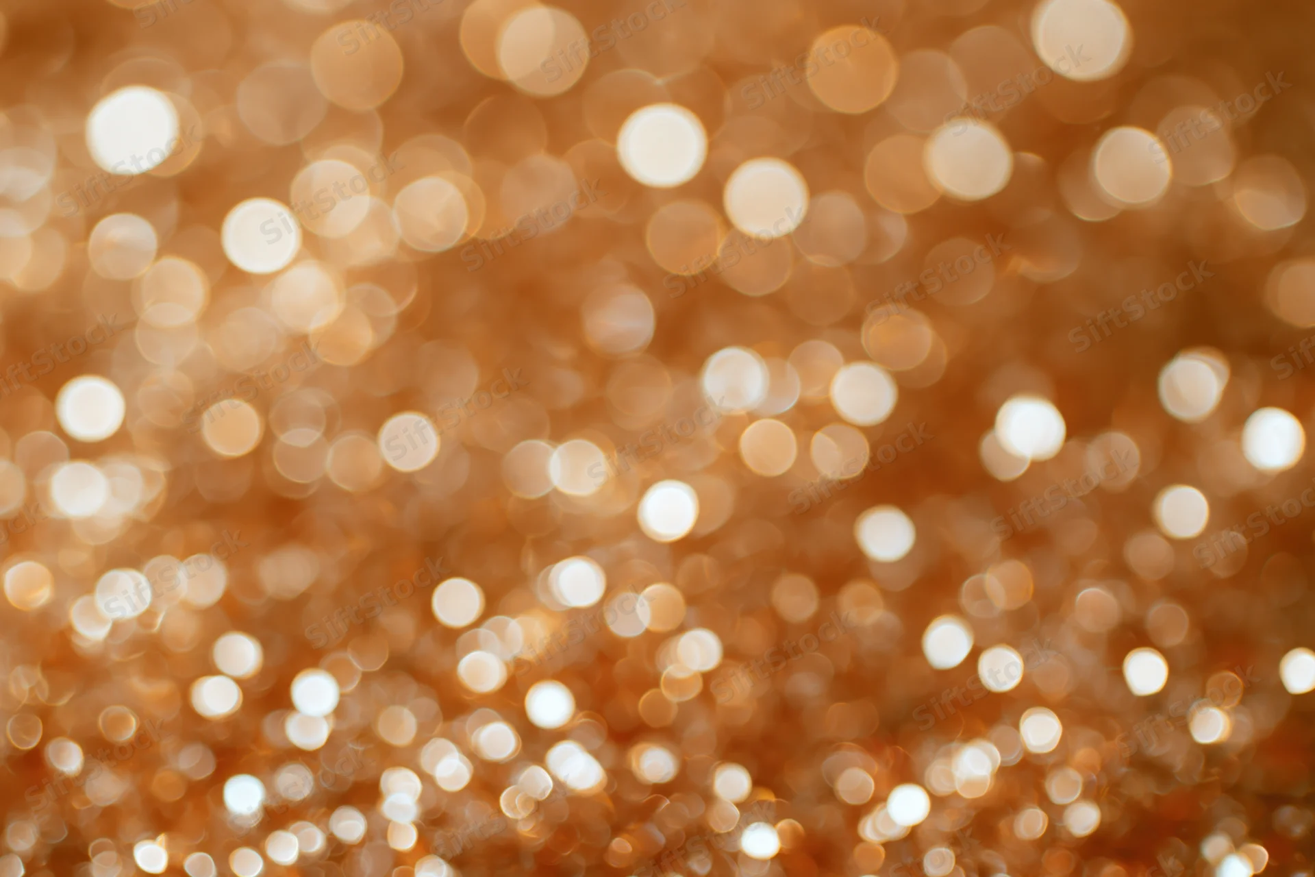 Abstract bokeh background of densely packed golden glitter shimmering softly in warm light