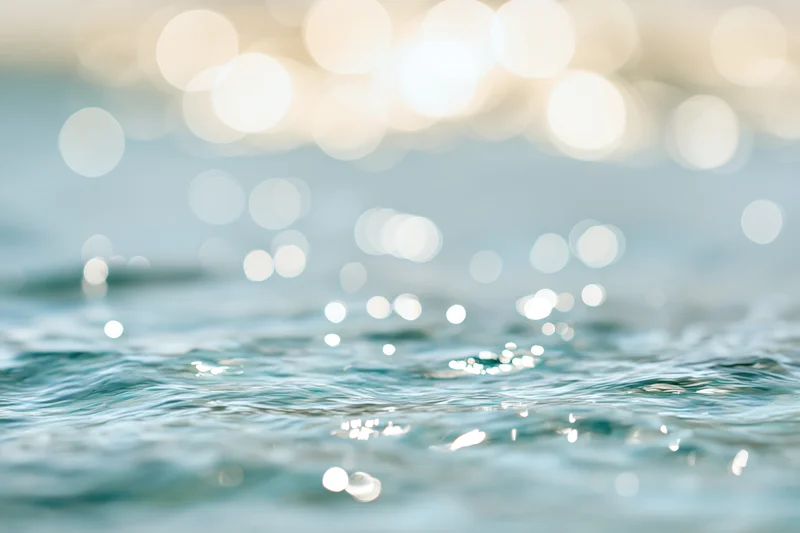 Sunlit ocean water surface with bokeh reflections and ripples