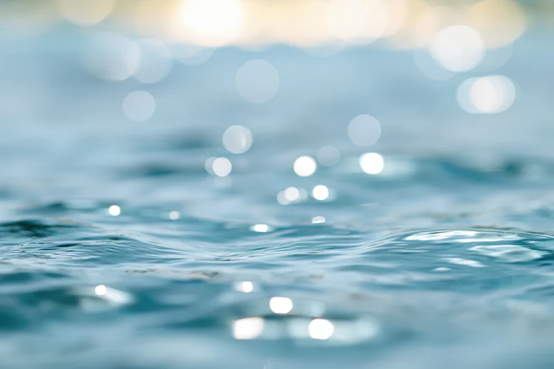 Sunlit ocean water surface with bokeh light reflections and gentle ripples