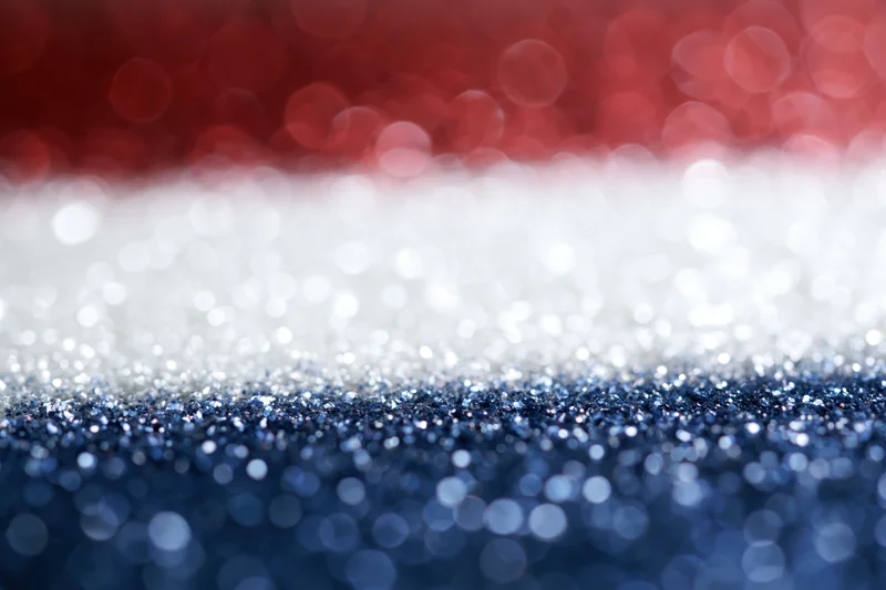 Abstract bokeh background with red white and blue glittery light circles fading into blur