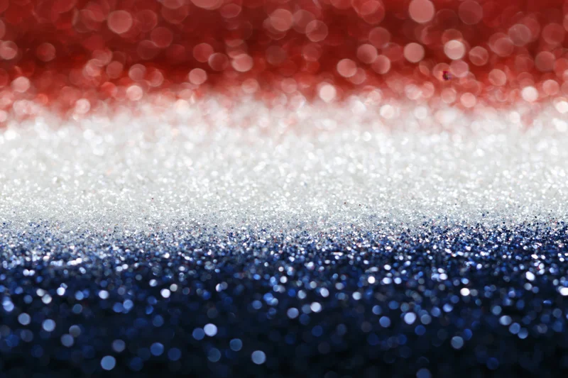 Abstract bokeh background with scattered light circles fading in red white and blue glitter texture