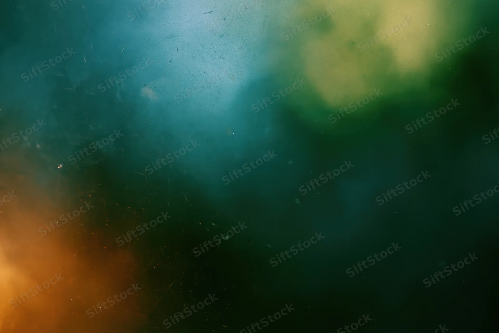 Abstract close-up of a dusty scratched glass surface with soft blurred colors and floating particles