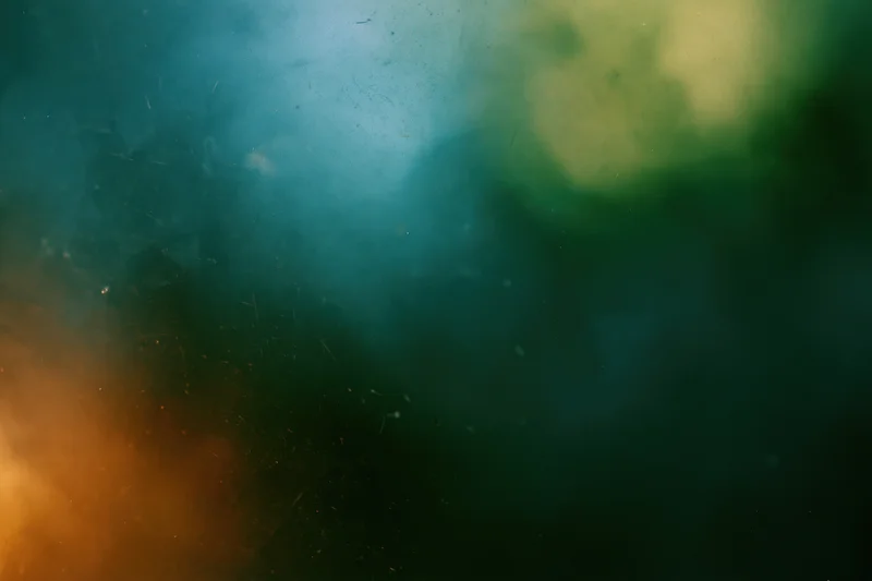 Abstract close-up of a dusty scratched glass surface with soft blurred colors and floating particles