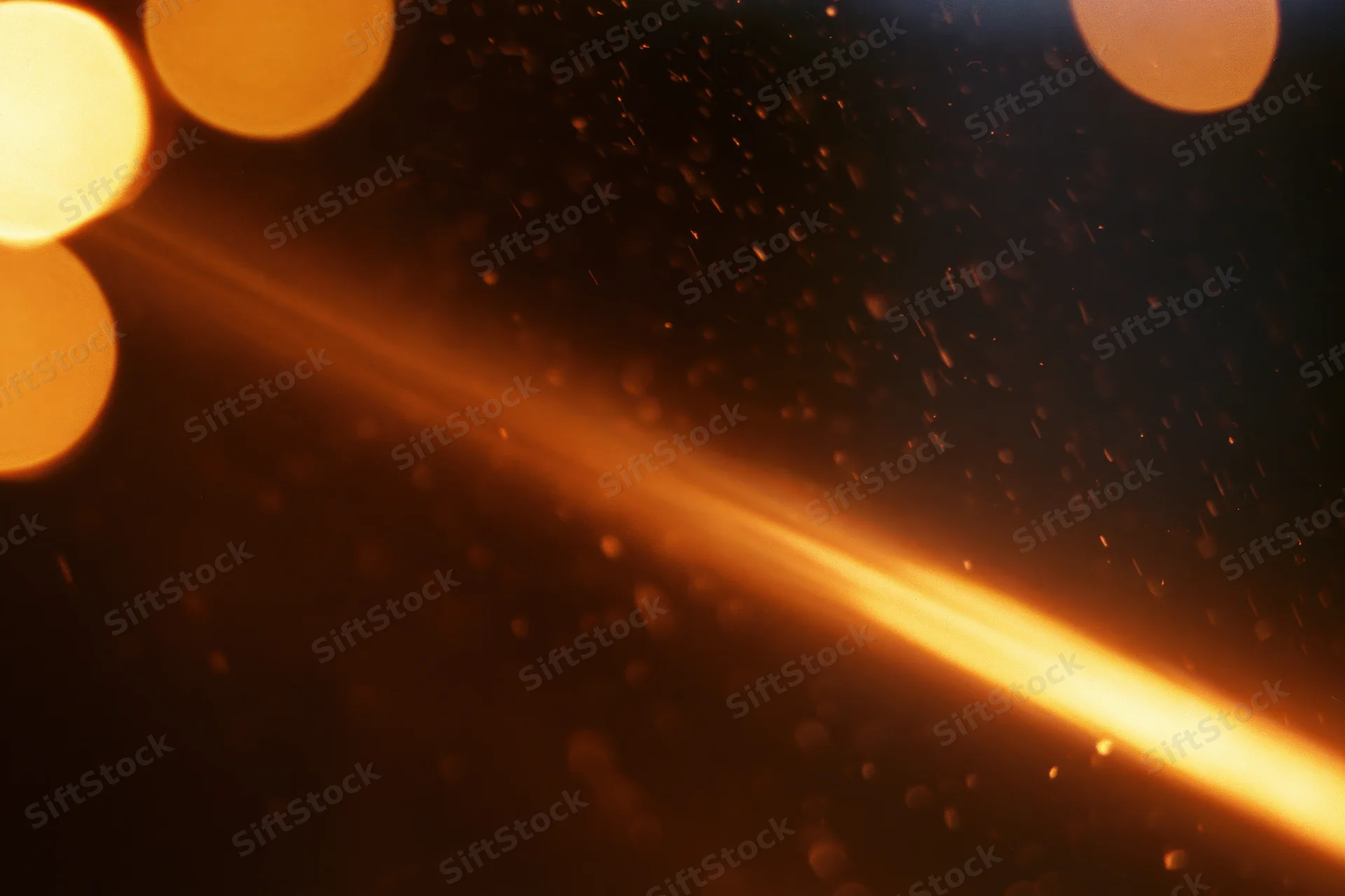 Warm amber light leaking across dark space with floating particles and bokeh highlights