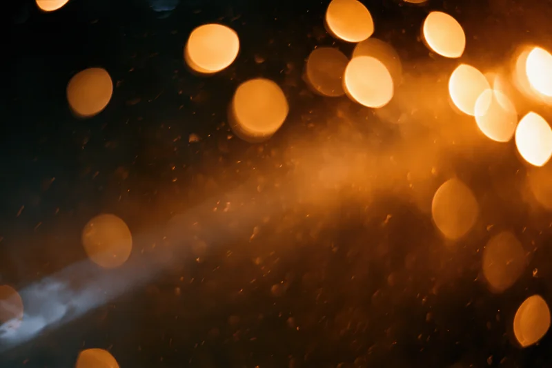 Warm amber bokeh lights glowing softly across a dark wet surface with rain droplets