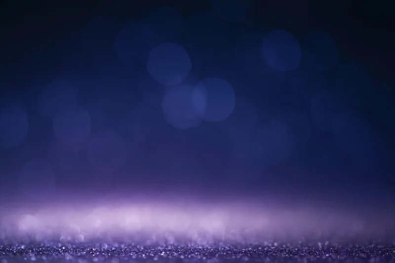 Dark studio backdrop with soft out-of-focus bokeh and glittery surface