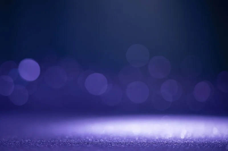 Dark studio backdrop with soft out-of-focus bokeh lights and glittering surface