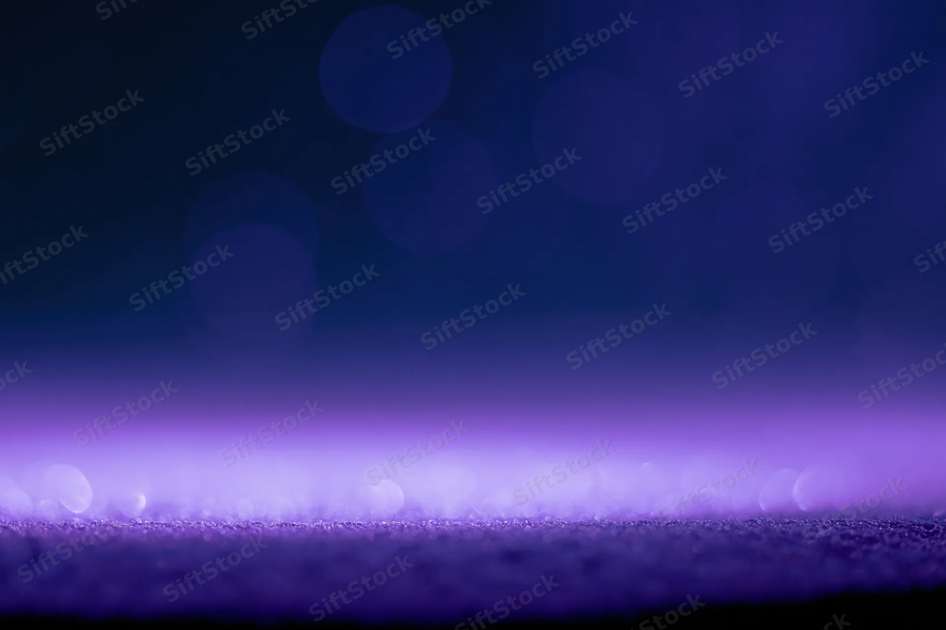 Abstract purple bokeh lights on dark studio background with soft glow and copyspace