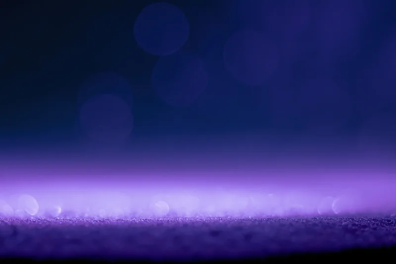 Abstract purple bokeh lights on dark studio background with soft glow and copyspace