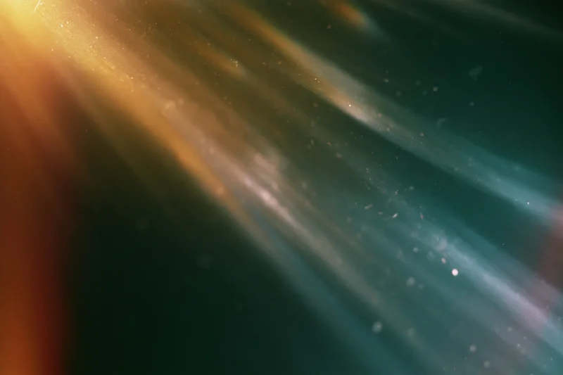 Diagonal light leak texture on dark dusty surface with floating particles