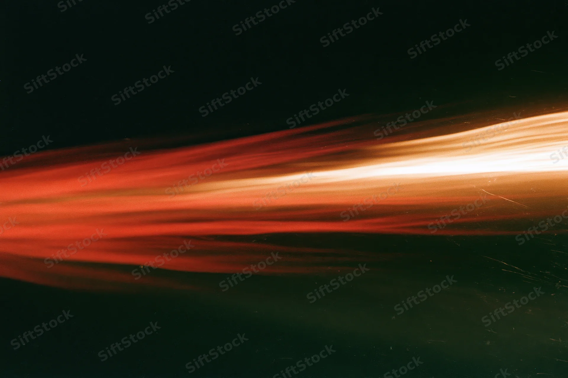 Horizontal light streaks blurring across dark background from long-exposure motion