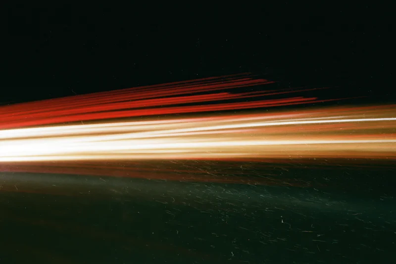 Horizontal light streaks from moving vehicles at night creating abstract motion blur