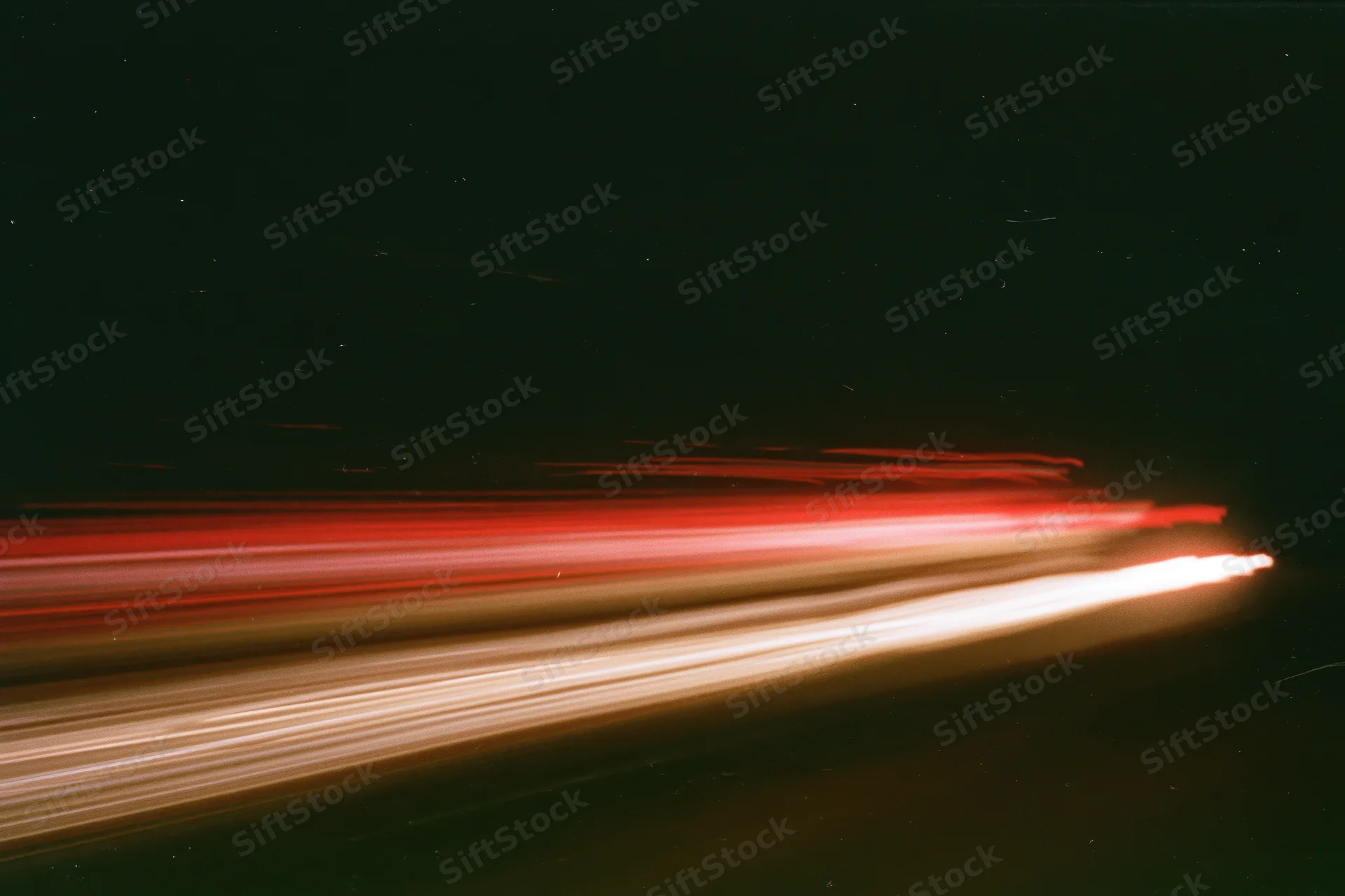 Horizontal light streaks from moving vehicles at night on a dark road