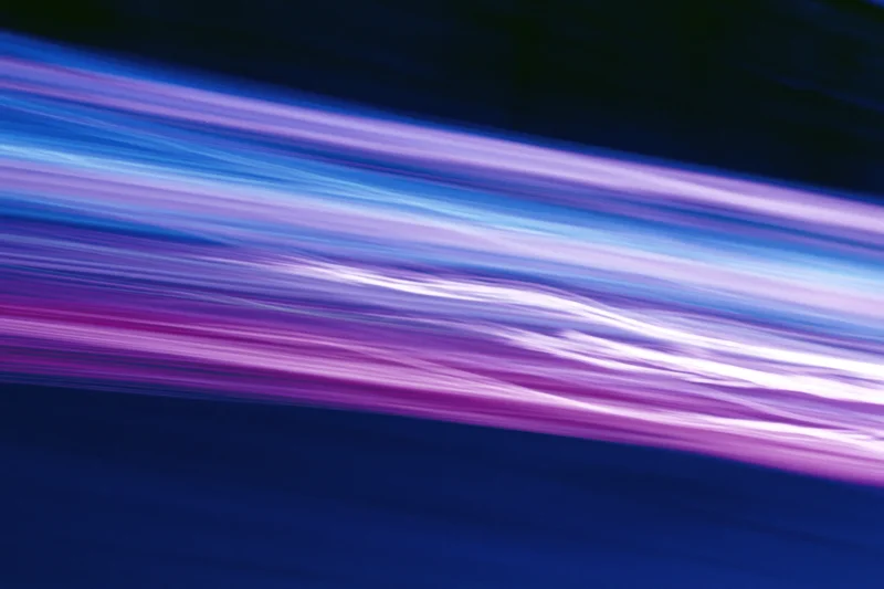 Abstract light streaks in motion blur across dark background