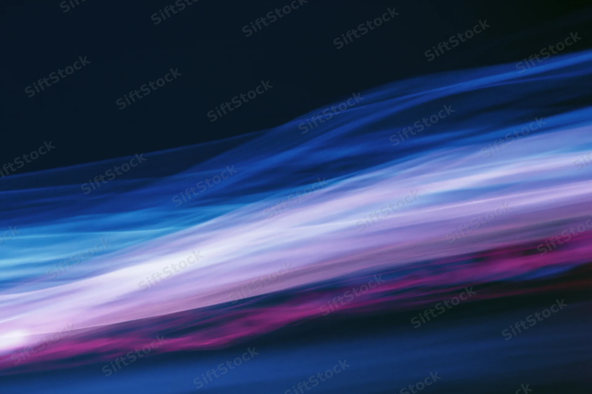 Abstract light streaks in motion blur across dark background