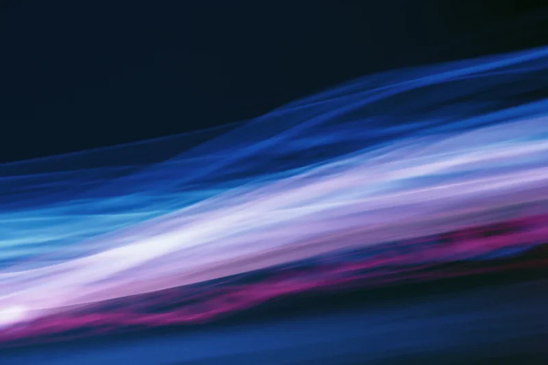 Abstract light streaks in motion blur across dark background