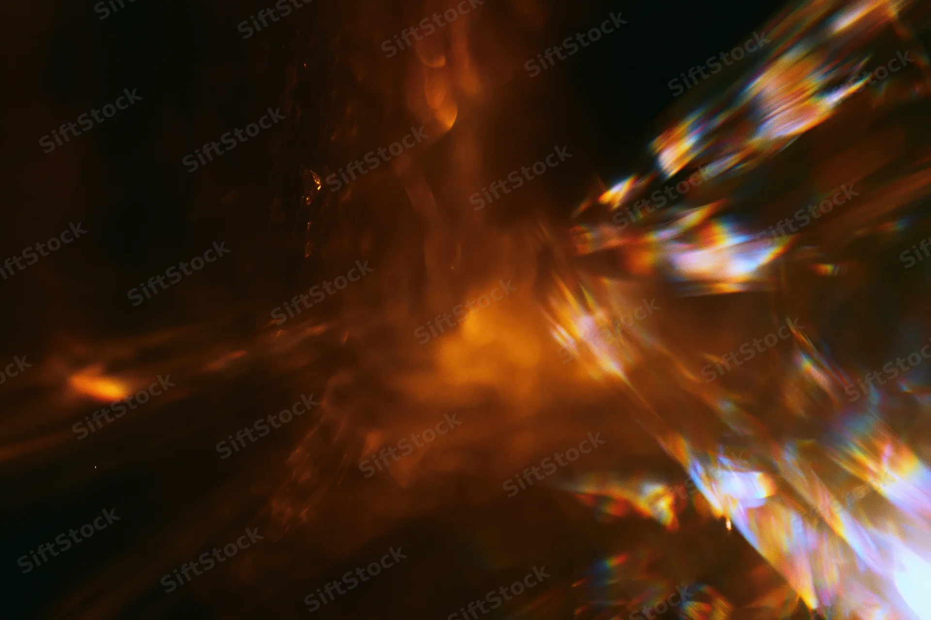 Abstract motion-blurred low-light scene with lens flare streaks and colorful light reflections