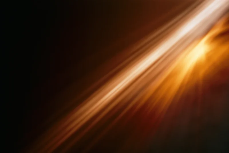 Warm light streaks moving diagonally across a dark background