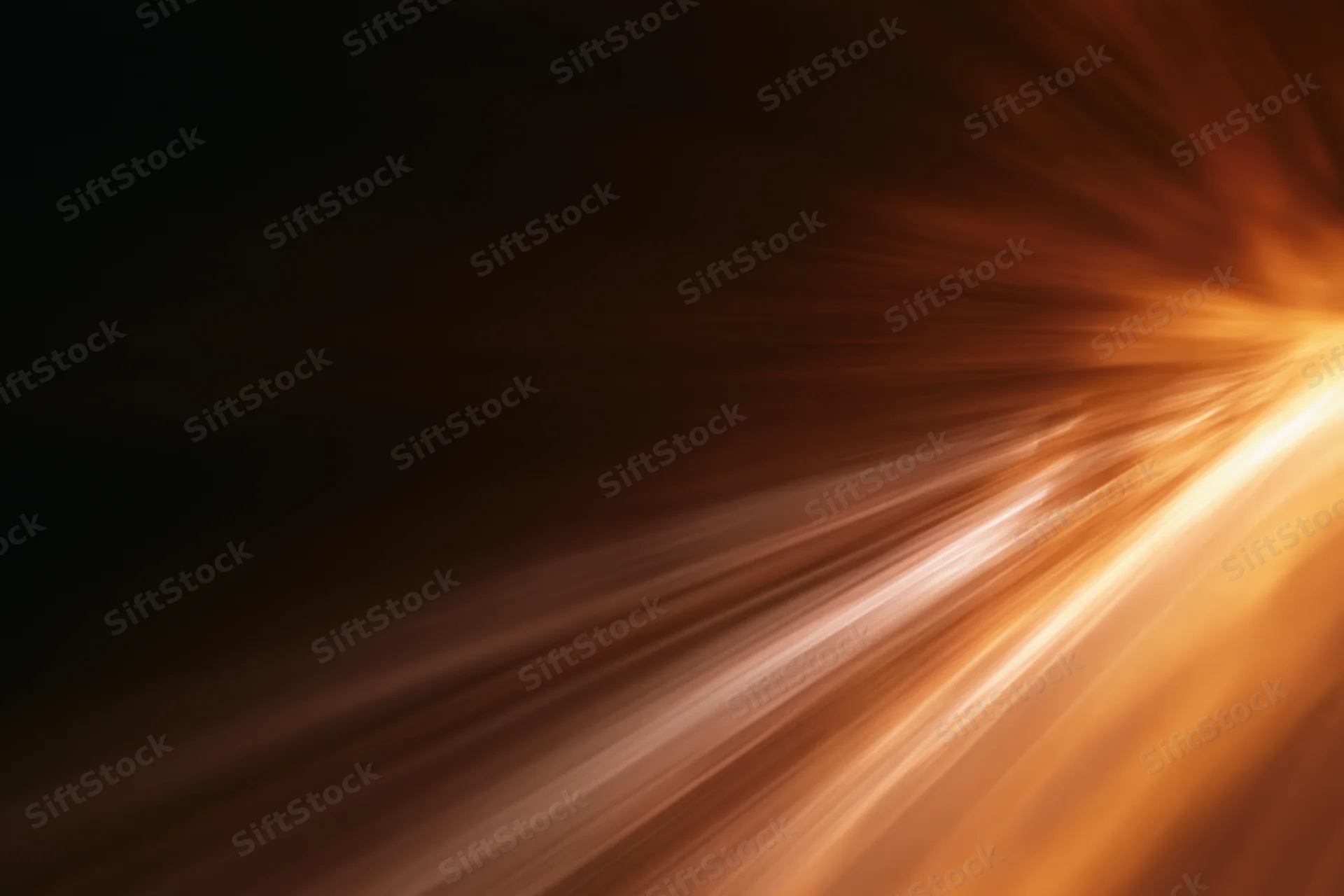 Warm light streaks moving diagonally across a dark background with motion blur