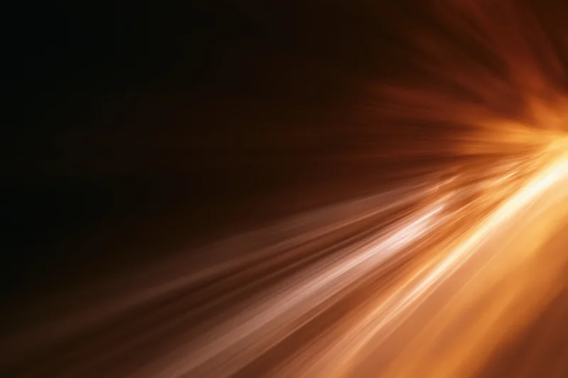 Warm light streaks moving diagonally across a dark background with motion blur