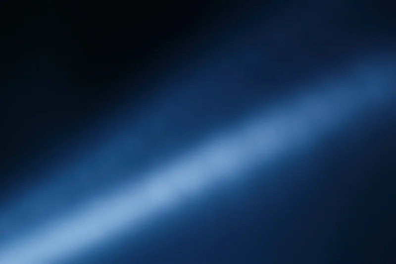 Diagonal blue light gradient fading from deep navy to soft glow across blurred abstract background