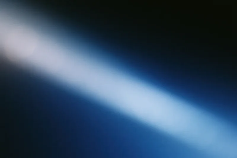 Diagonal light gradient fading from deep navy blue to soft white across blurred abstract background