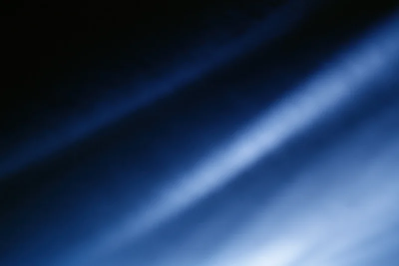 Diagonal light gradient fading from deep navy to bright white across abstract blurred background