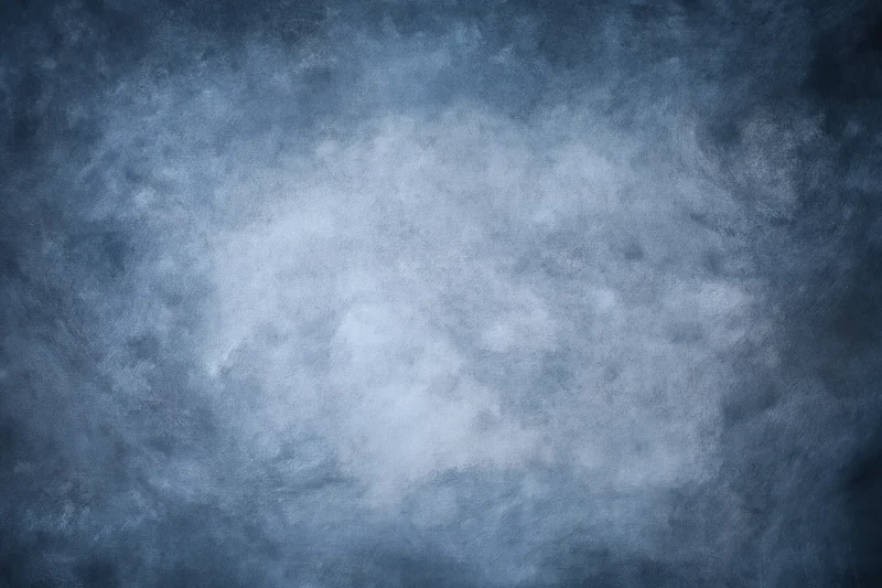 Abstract textured blue-gray backdrop filling the frame with soft light gradient and vignette effect