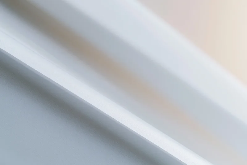 Diagonal white and grey streaks across a smooth surface with soft blur and copyspace