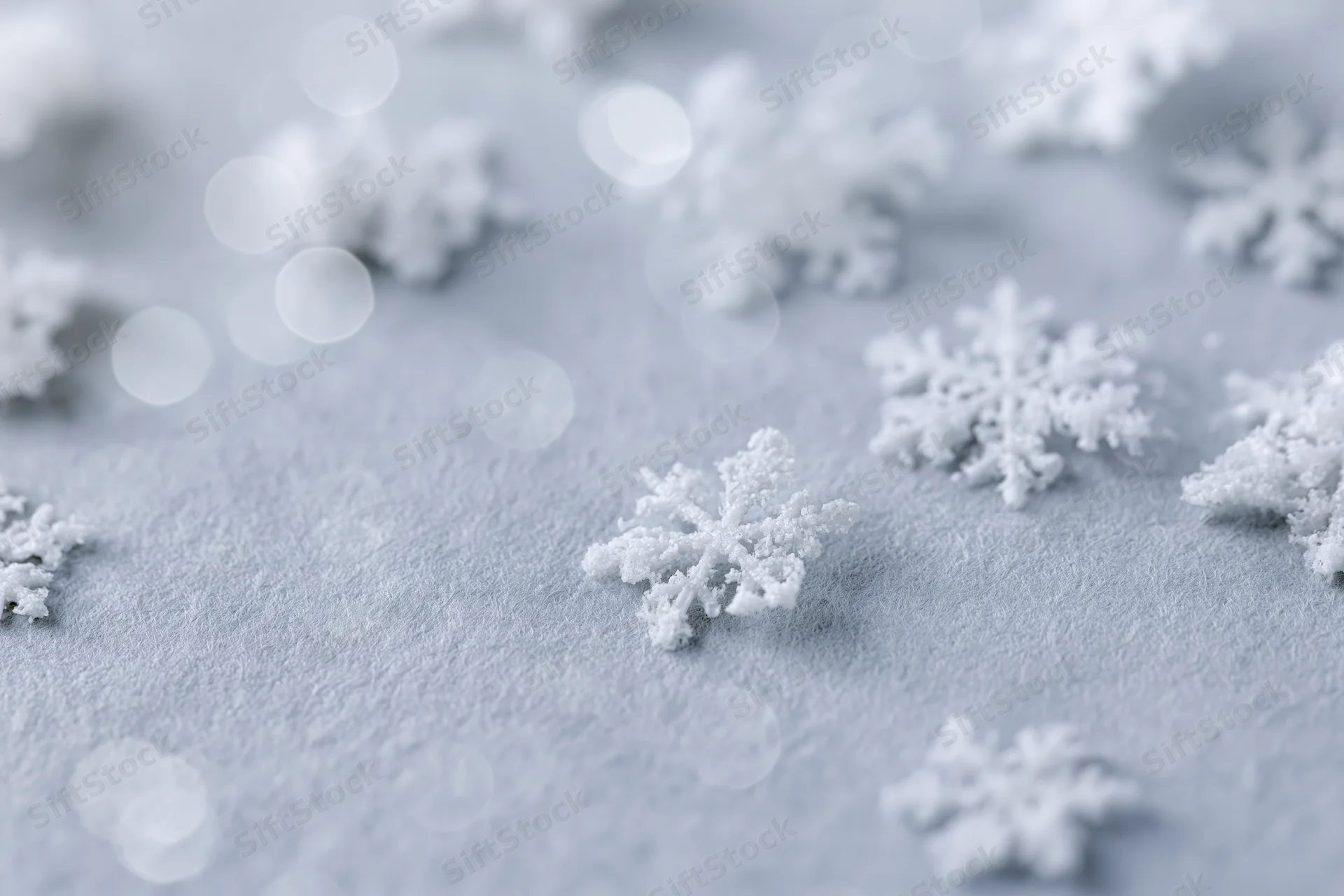 Snowflakes scattered on a frosty surface with soft bokeh lights in the background