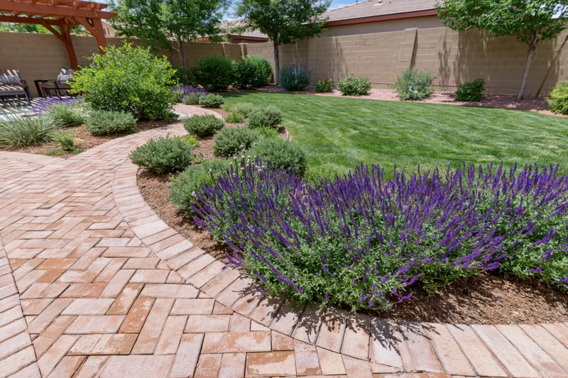 Professionally landscaped backyard with curved brick patio, green lawn, and purple lavender border