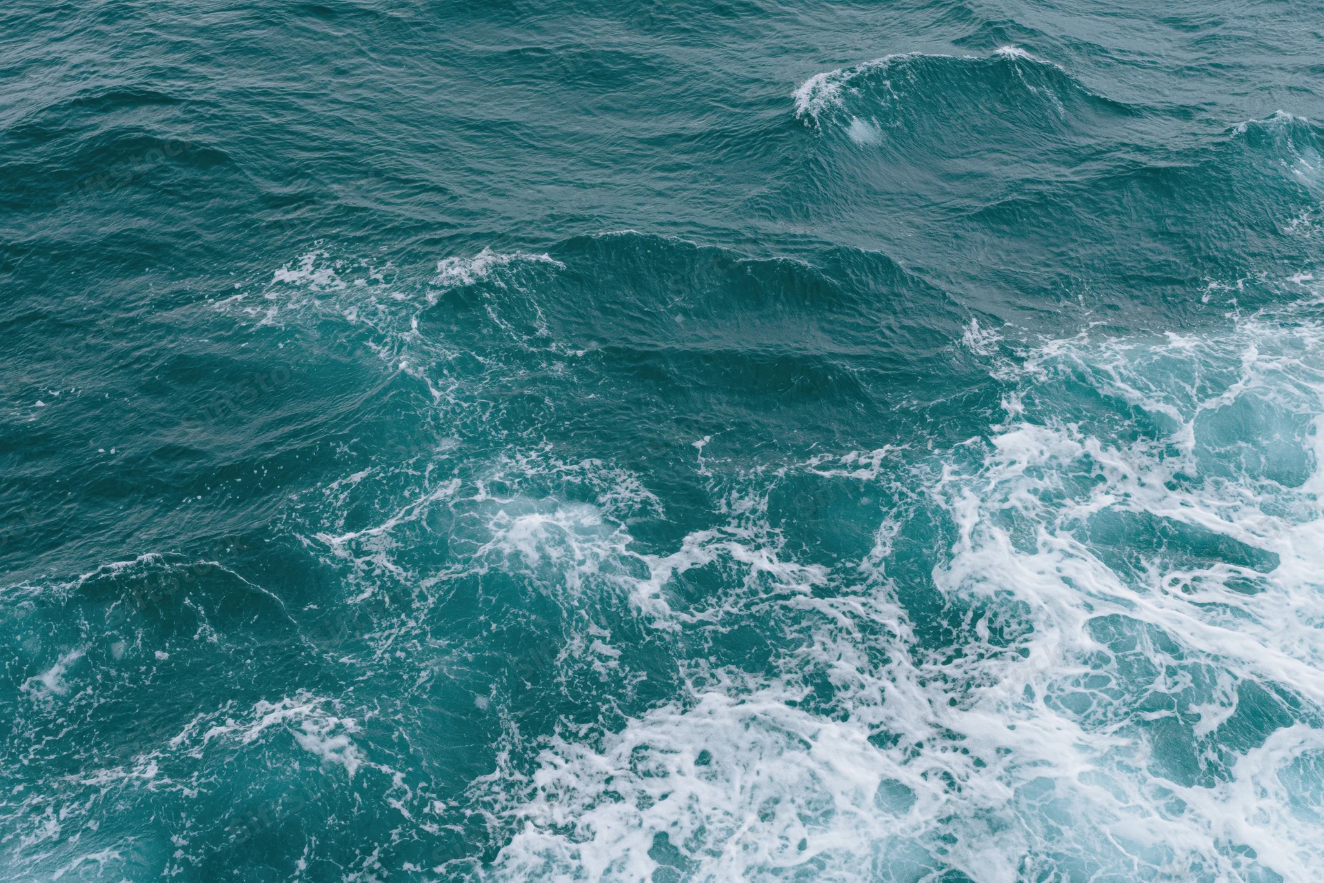 Open ocean surface with small ripples and white foam from breaking waves