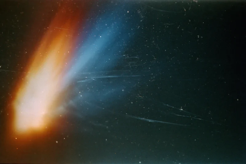 Light leak artifact in a dark space scene with orange and blue streaks across a starfield