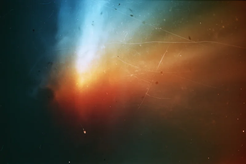 Light leak artifact on aged film scan with blue and orange gradient and visible scratches and dust