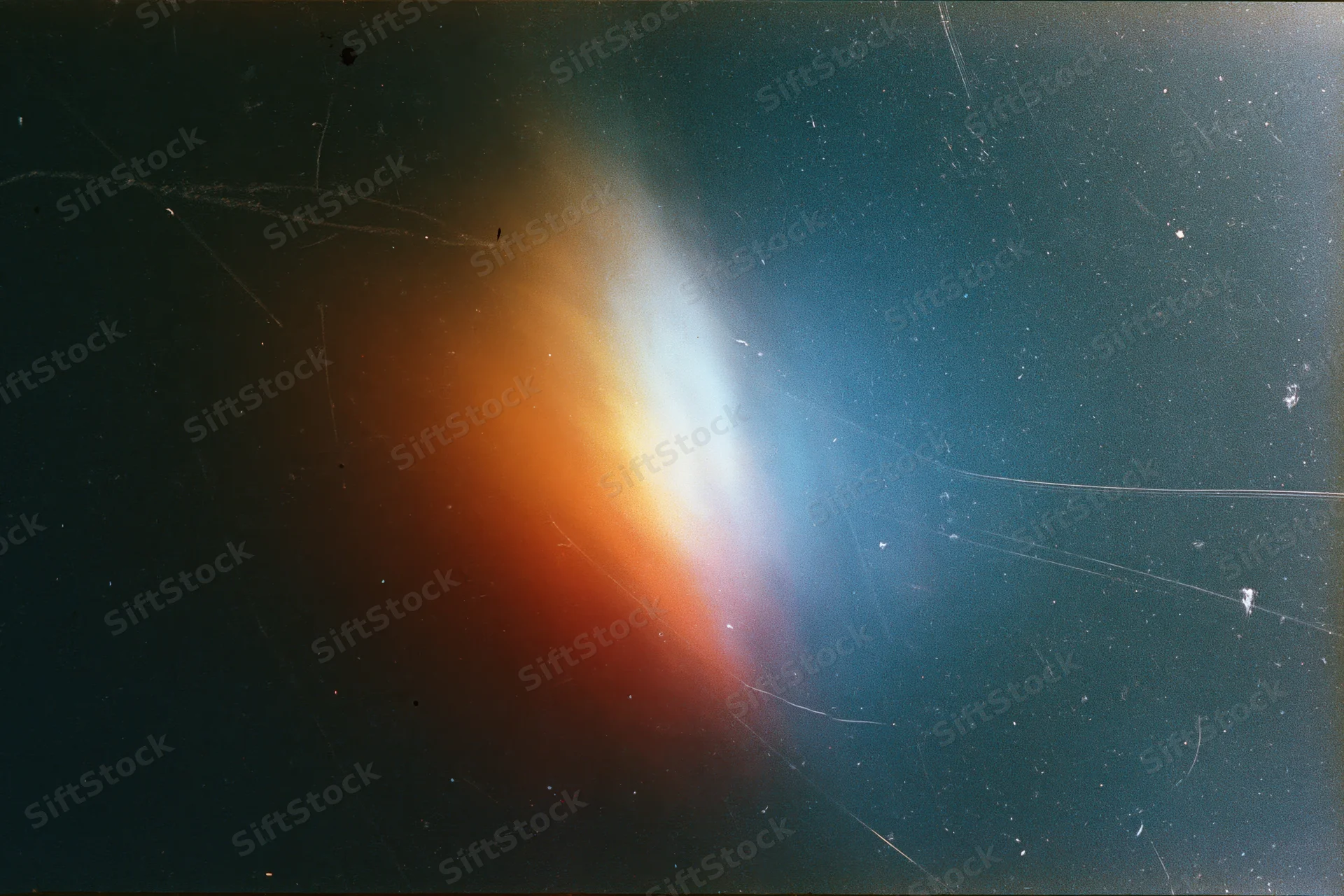 Light leak artifact in aged film scan showing orange and blue gradient glow against dark space background