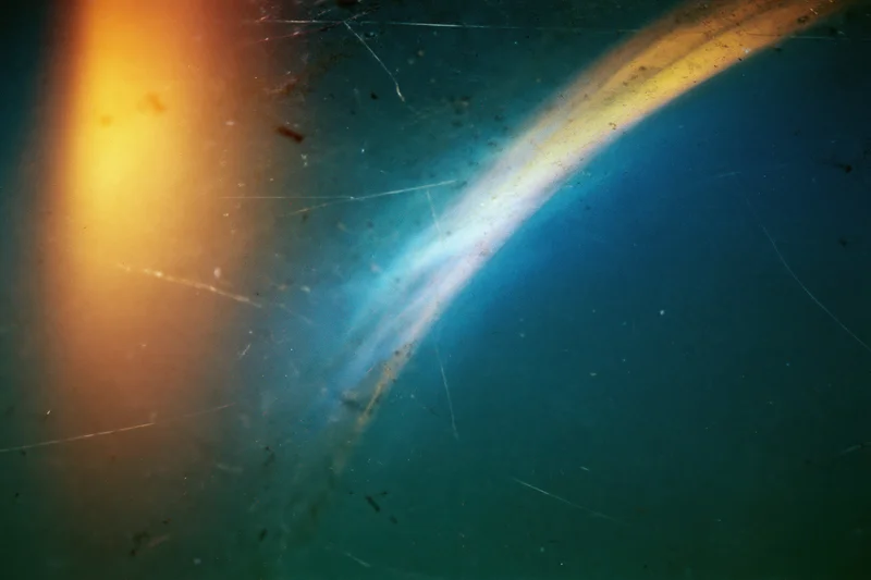 Aged film scan with light leak and lens flare across a dark blue gradient background