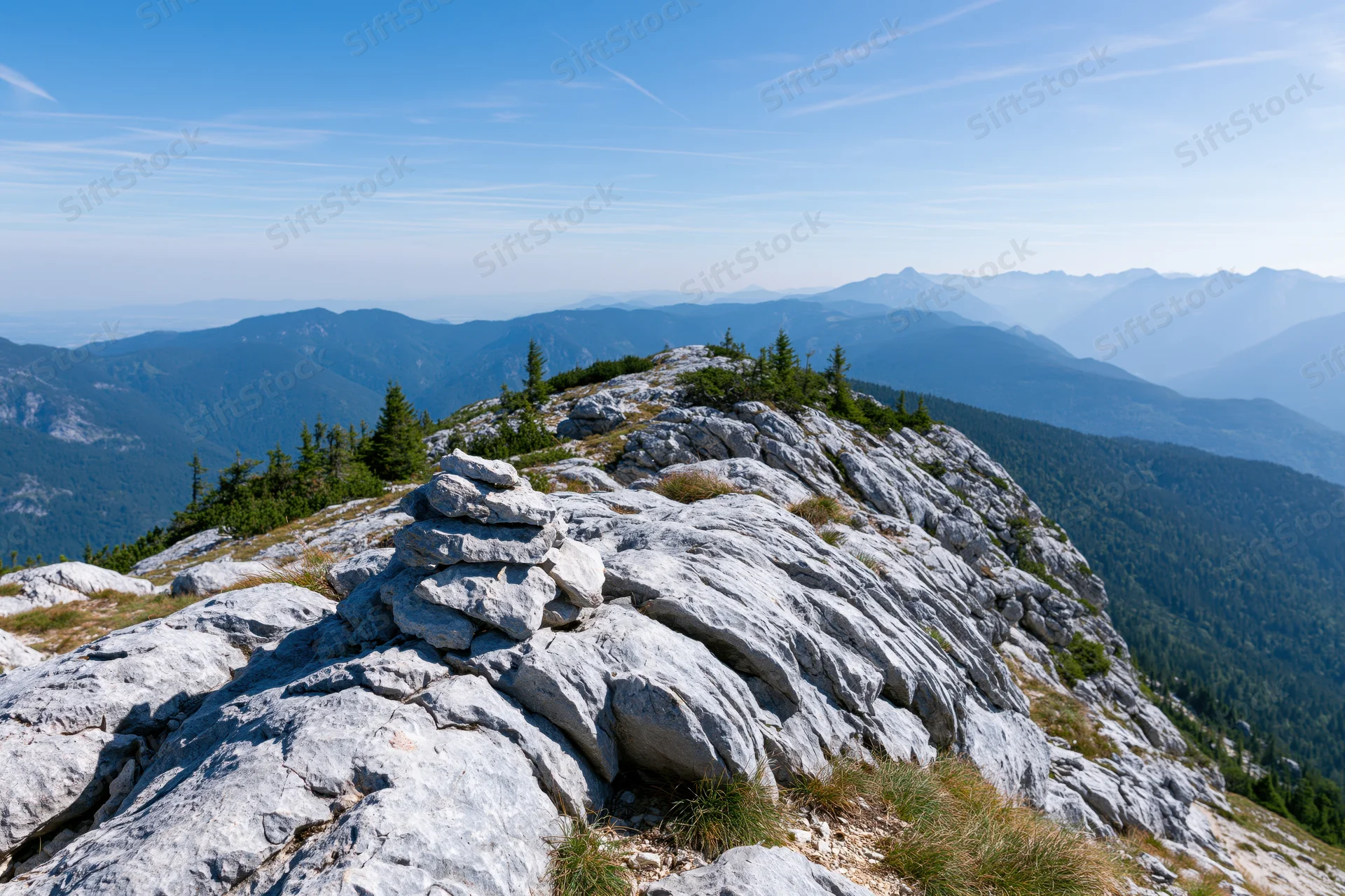 Stone cairn on rocky alpine ridge overlooking mountain valley