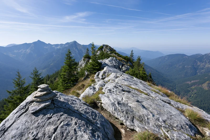 Rocky alpine ridge with a small stone cairn in the foreground overlooking a mountain valley