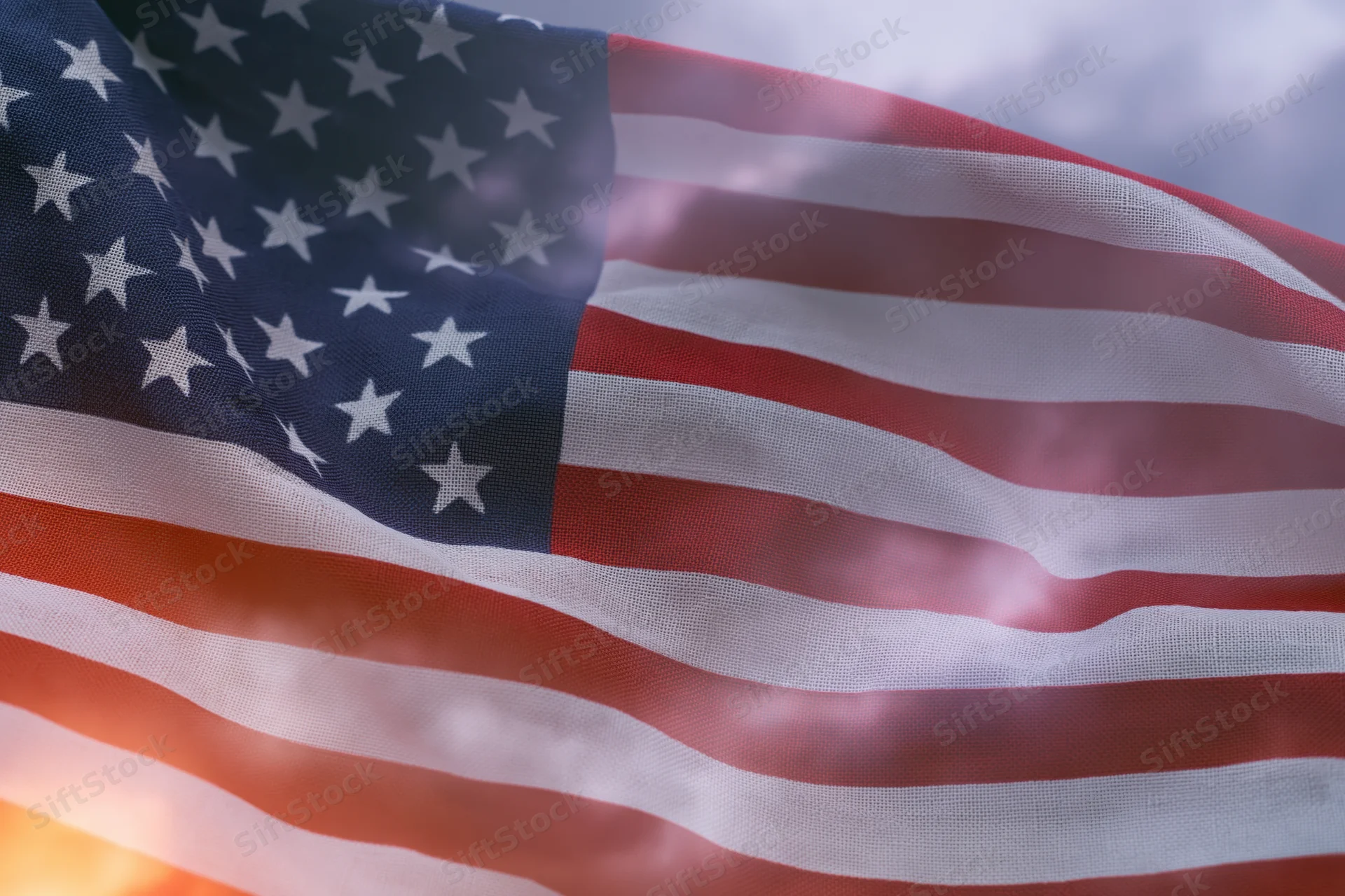 American flag rippling in wind filling the frame with stars and stripes against sky