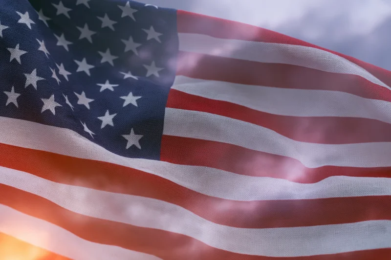 American flag rippling in wind filling the frame with stars and stripes against sky