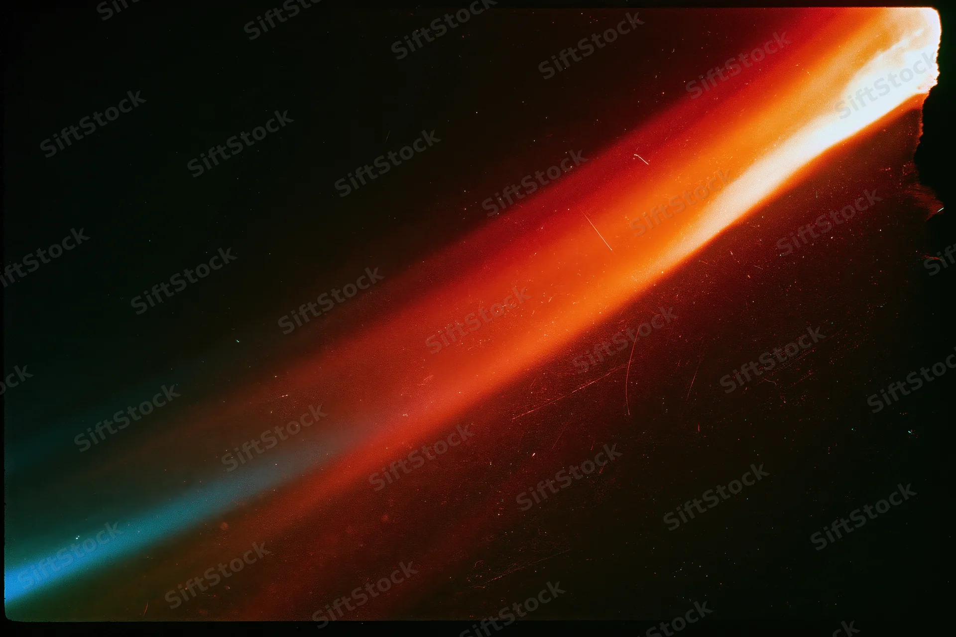 Diagonal light leak overlay in red orange yellow and blue on black background