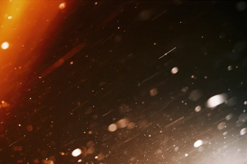 Abstract bokeh light particles with warm orange glow and film grain texture overlay