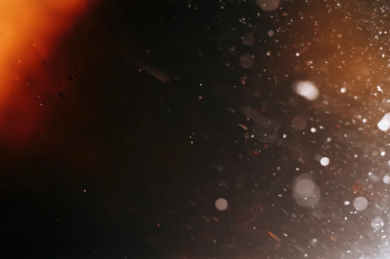Analog film scan texture with visible damage and light flares, showing grain and particles against a dark background