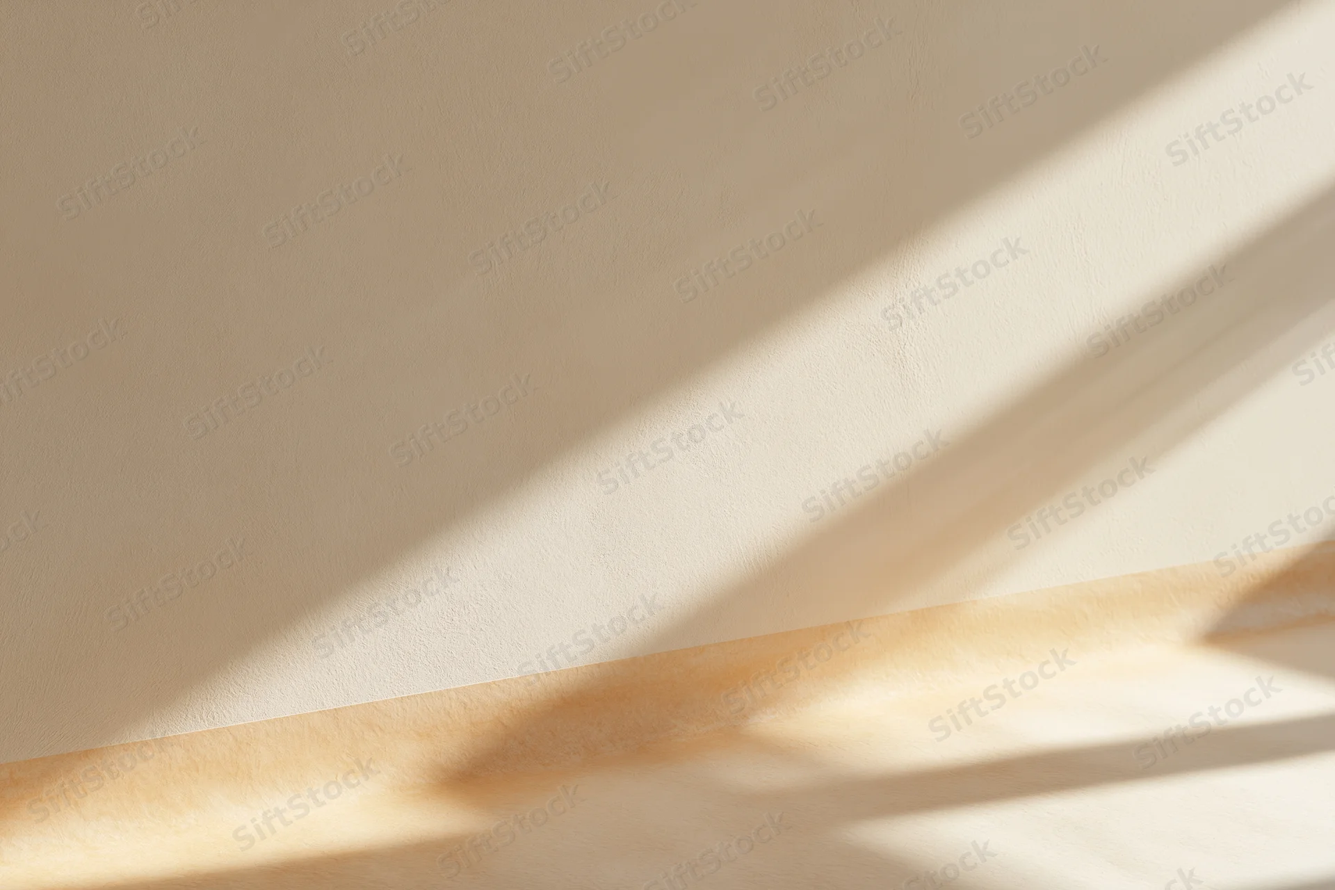 Beige plaster wall meeting smooth wooden floor with sunlight and shadows in empty interior