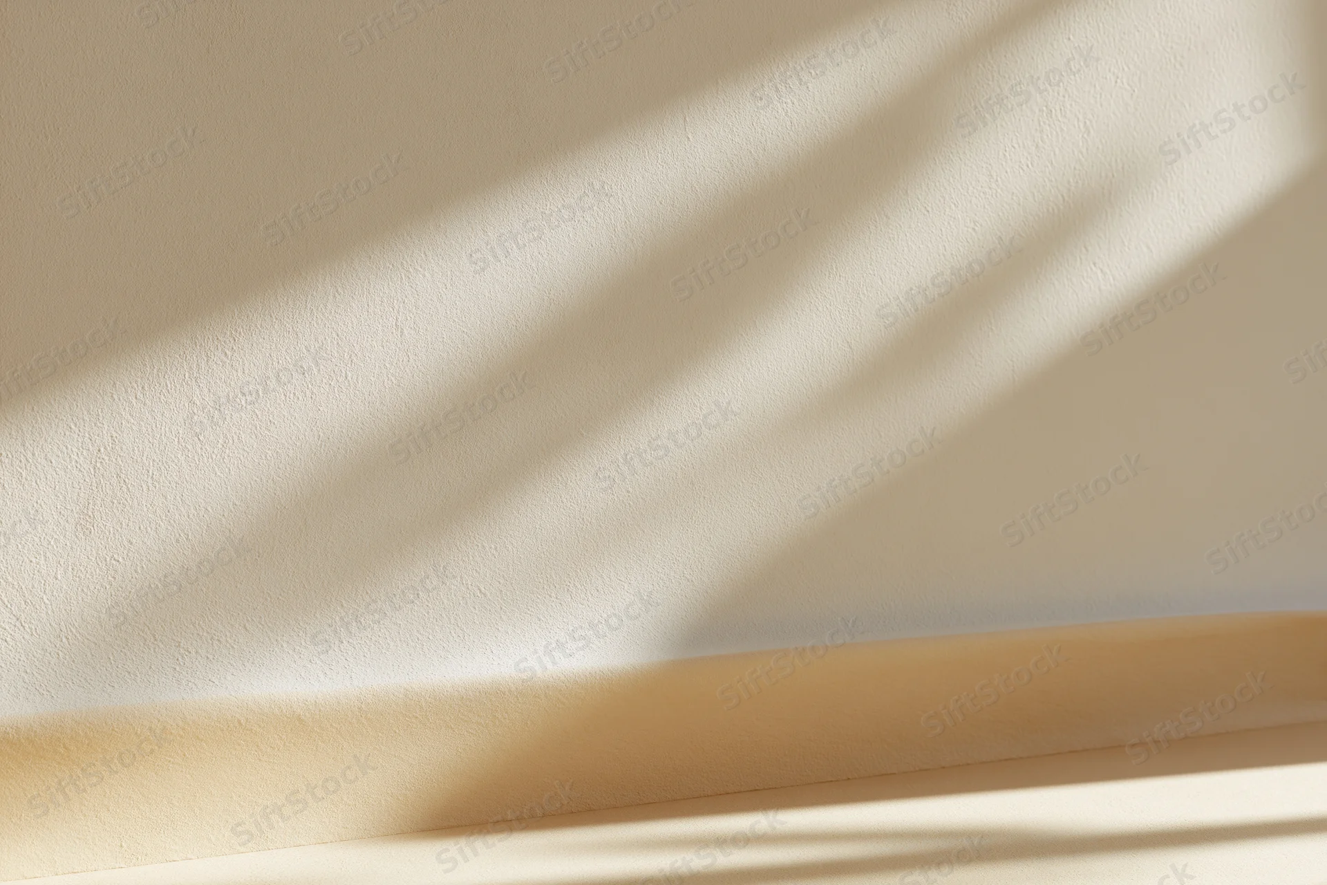 Beige plaster wall meeting smooth surface below with sunlight casting diagonal shadows