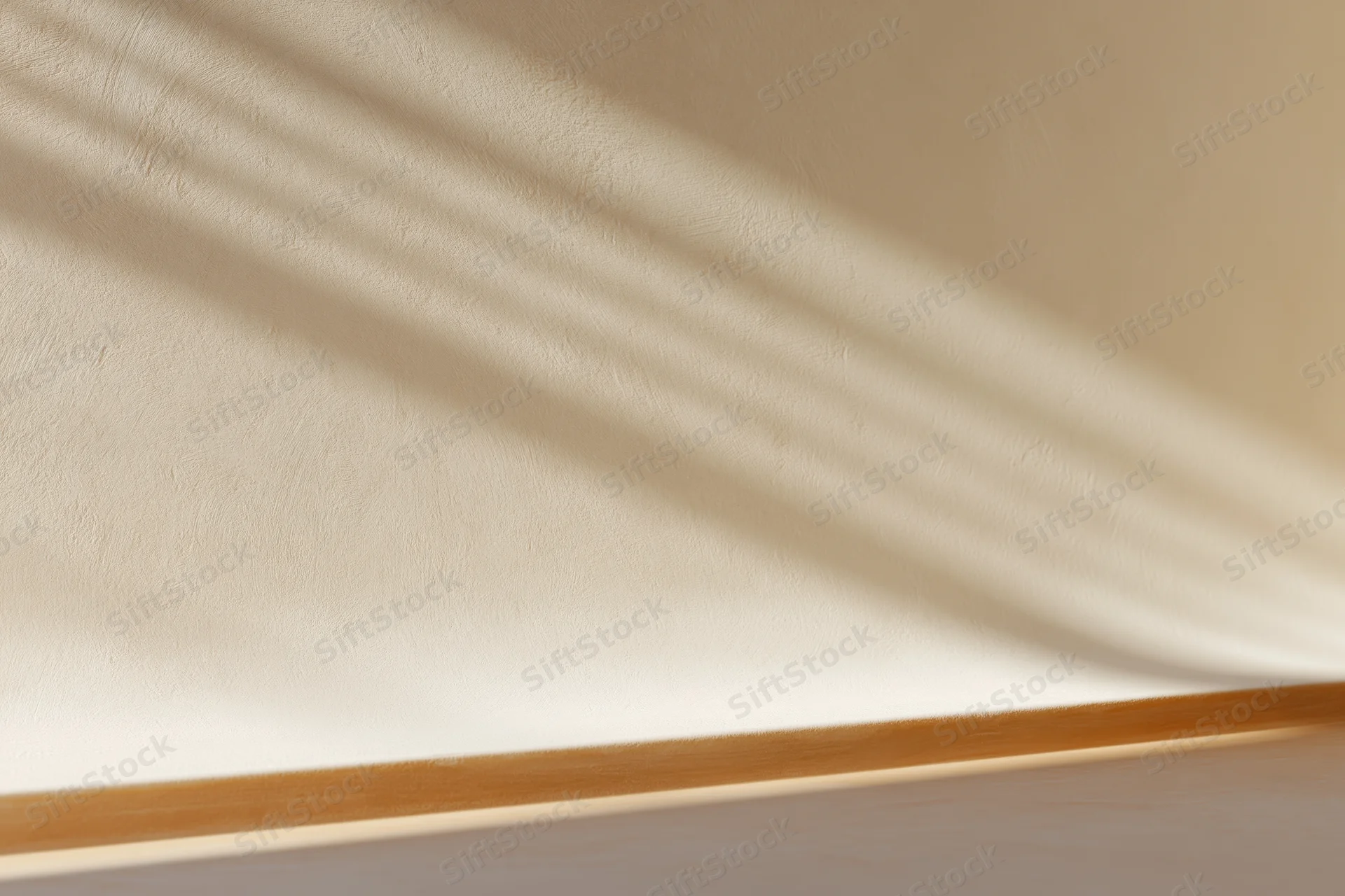 Beige plaster wall meeting smooth surface below with shadow stripes and wooden trim