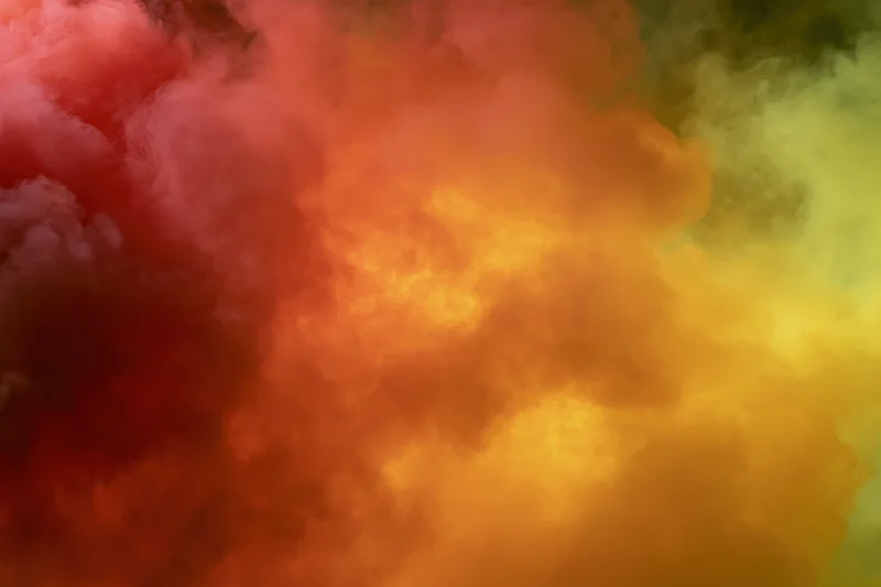 Billowing clouds of colored smoke filling the frame with red, orange, yellow and green hues