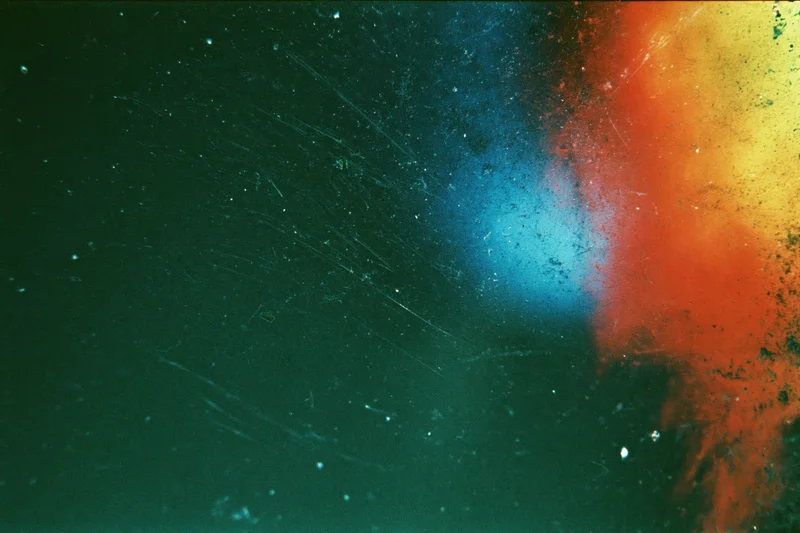 Damaged 35mm film frame with heavy light leak and color bleed across the surface