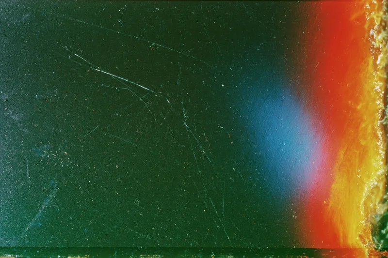 Damaged 35mm film frame with light leak and color gradient across the surface